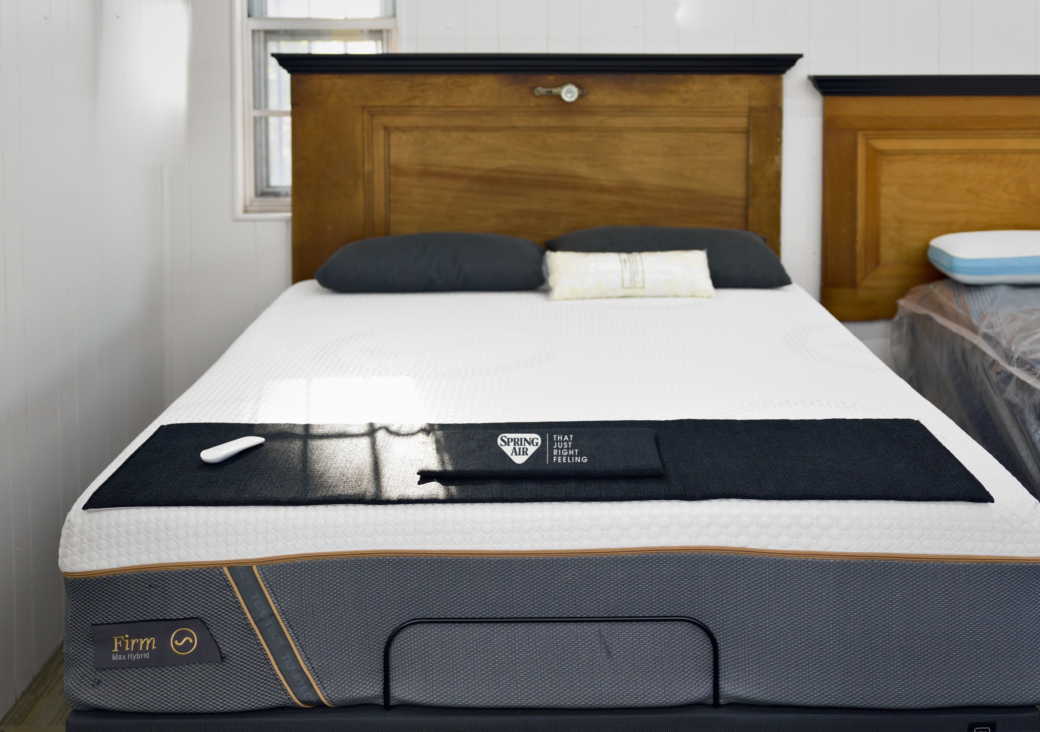 A Spring Air mattress on an adjustable base in the showroom, under a wood headboard